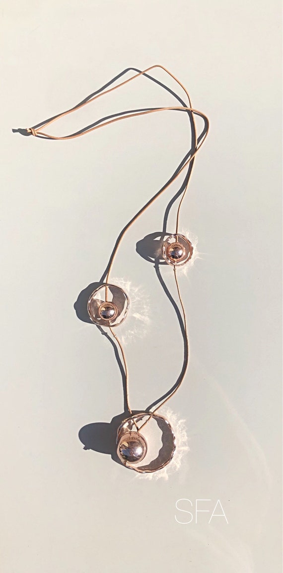 Stunning rose gold orbital geo necklace, on a long taupe thread.