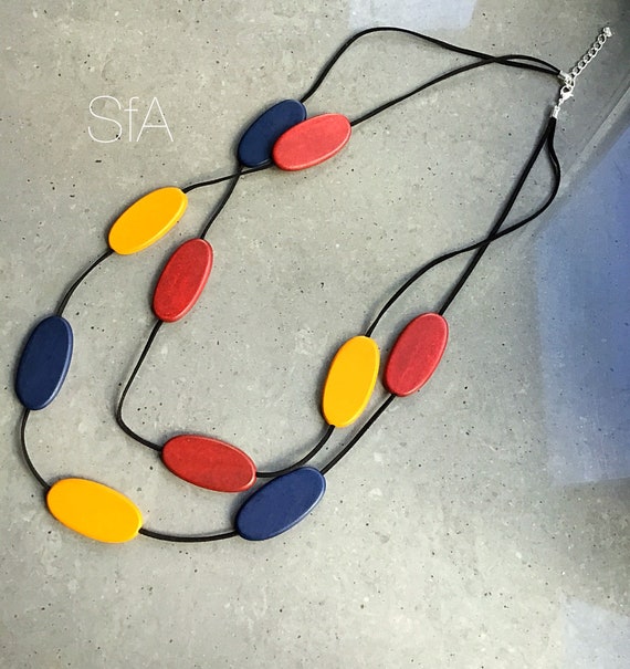 Long necklace made from wood, with multi coloured oval discs, with double black suede thread.