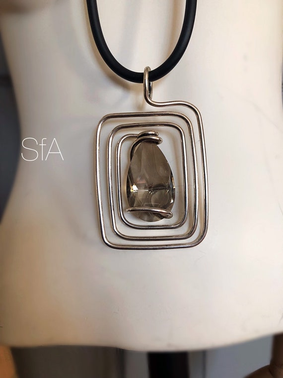 Lagenlook necklace. Large twisted rectangle wire pendant with central large teardrop glass crystal, on thick rubber necklace.
