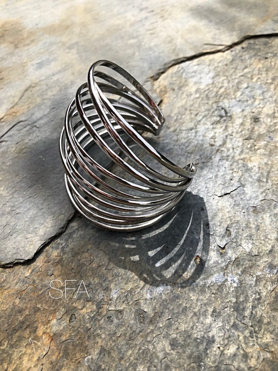 Stunning geo, polished silver. With kriss kross cage effect, with an open back. Fits all sizes.