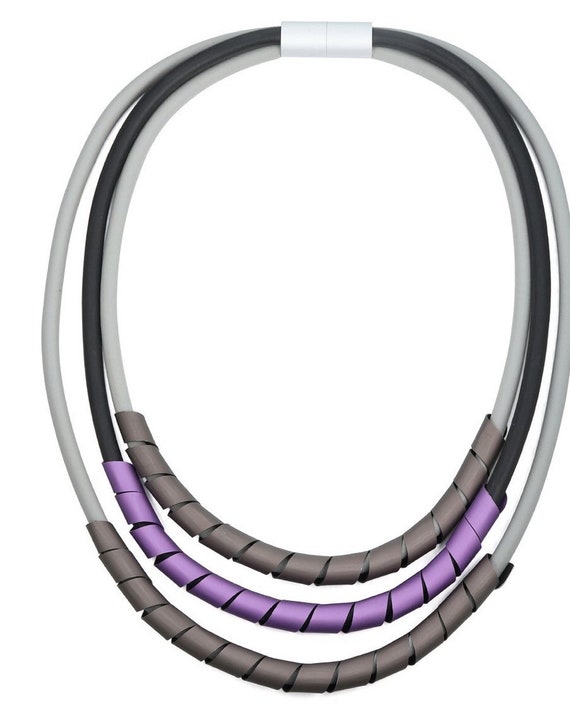 Multi strand rubber necklace, grey and black shades with frosted purple and graphite matching twisted metal pendant.