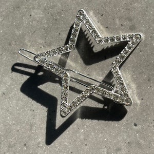 May include: A silver star-shaped hair clip with clear rhinestones. The clip is open and ready to be used.