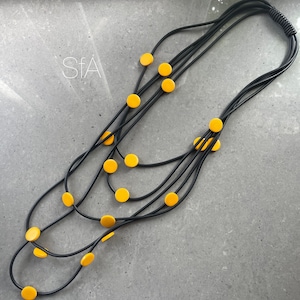 Multi strand black rubber necklace, with yellow wooden round shapes, lightweight.