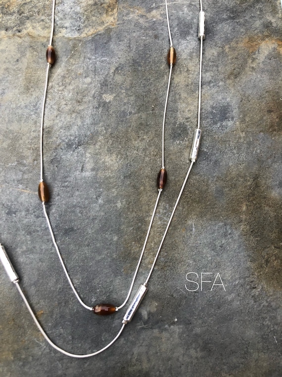Long silver tone necklace with tiger eye beads on first chain, with solid silver tubes on longer chain