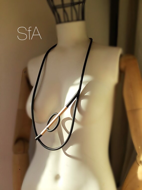 Lagenlook abstract necklace with a minamalist feel. In black rubber with gold frosted bar.