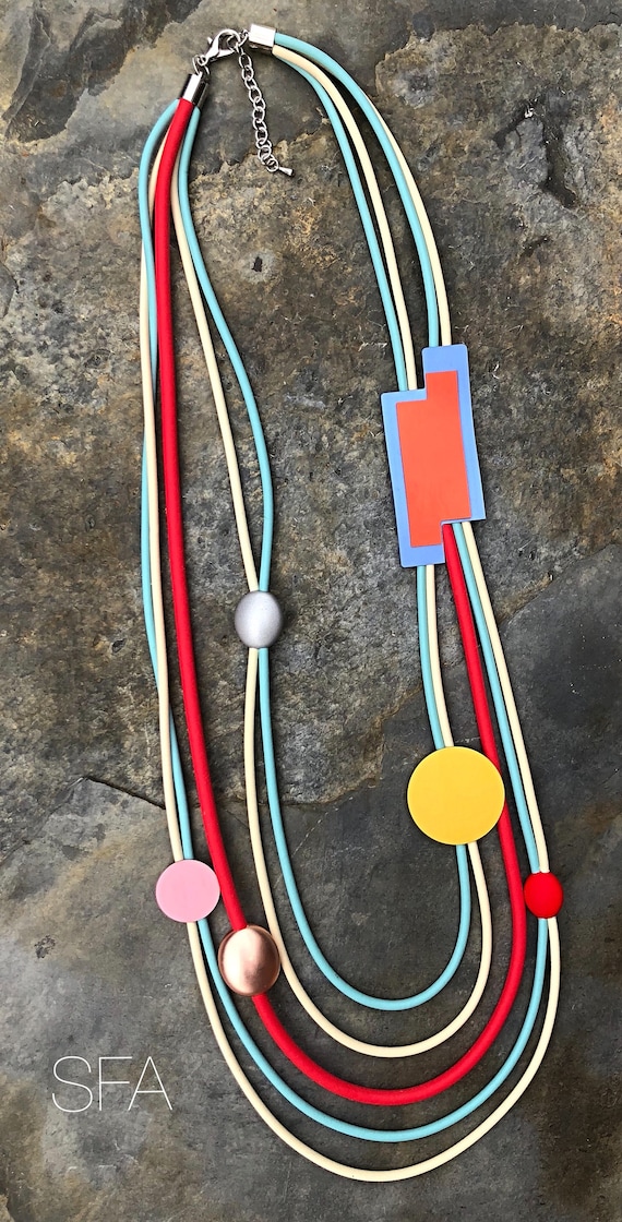 Lagenlook, Geo, multi thread rubber necklace, in red, cream and blue thread, with a dusky pink disc and gold frosted geo shapes.