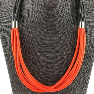 Könnte beinhalten: Eine mehrsträngige Halskette in Schwarz und Orange. Die Halskette besteht aus einem dicken, seilartigen Material und hat ein schlichtes, modernes Design.