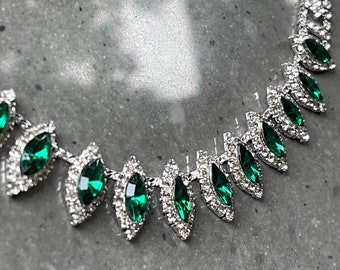 May include: A silver-toned necklace and earring set featuring marquise-cut emerald green crystals surrounded by small clear rhinestones. The jewelry pieces are arranged in a repeating pattern. The text SunfloweAngel UK is visible at the bottom.