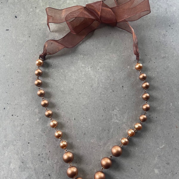 Collana di perle di bronzo con chiusura a laccio in raso di taglio. Super glamour.
