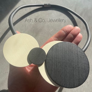 Black Rubber single thread short necklace, with large and small wooden black and cream discs, lightweight.