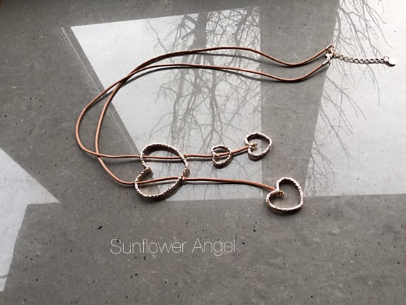 Gold multi heart necklace, on a caramel leather thread with various shaped gold hearts.