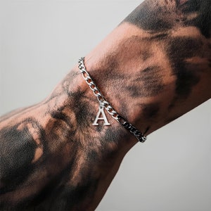 May include: A silver chain bracelet with a silver charm in the shape of the letter A.