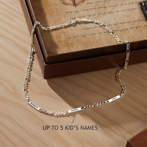 May include: A silver necklace with three name bars, each engraved with a name: Brandon, Robert, and James. The necklace is displayed on a wooden surface, with the text "Up to 5 Kid's Names".