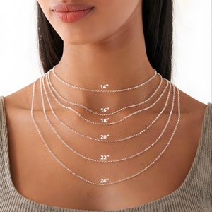 May include: A close-up of a model wearing a silver chain necklace in various lengths, from 14 inches to 24 inches. The necklace is shown on a model wearing a beige shirt.