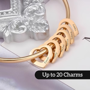 May include: Gold-toned bangle bracelet with multiple heart-shaped charms. Each charm is engraved with a different name, including Eason, Hailey, Rachel, Nance, Sabina, and Valery. The bracelet has a text overlay that reads "Up to 20 Charms".