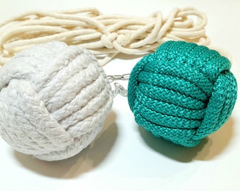 May include: Two rope balls, one white and one teal green, connected by a metal chain. The rope balls are made of tightly woven rope and are about the size of a tennis ball.