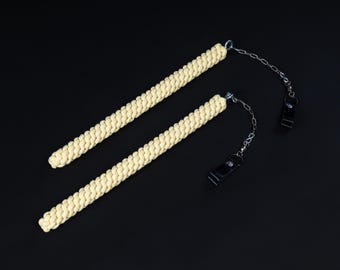 May include: Two fire poi with cream-colored woven handles and silver chains. The black clips are attached to the chains. The poi are set against a black background.