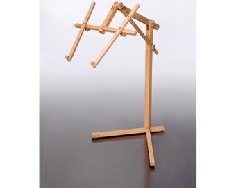 May include: A wooden stand with adjustable arms for displaying embroidery hoops. The stand has a wide base and a tall, slender post.