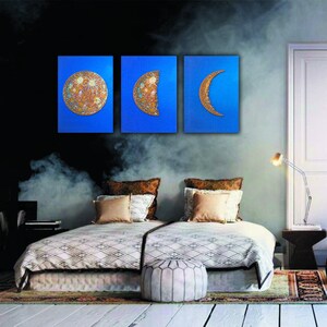 May include: Three blue canvas paintings with gold moon phases. The first painting shows a full moon, the second shows a half moon, and the third shows a crescent moon.