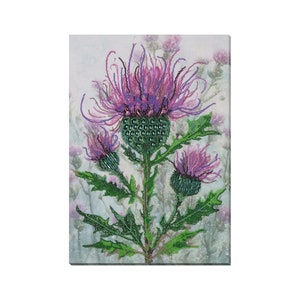 Puede incluir: Un primer plano de un bordado de cuentas de una flor de cardo púrpura con hojas y tallos verdes. El fondo es gris claro con una textura sutil.