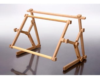 May include: A wooden embroidery stand with adjustable height and a removable top bar. The stand is made of natural wood and has a light brown finish.