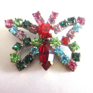 Puede incluir: Broche de mariposa vintage con marco de metal plateado. El broche presenta una gran piedra central roja y está adornado con una variedad de pedrería colorida en tonos rojos, rosas, verdes y azules. Una pieza de joyería clásica.