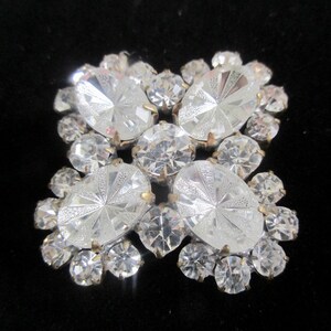 May include: A vintage brooch with a cluster of clear faceted rhinestones in a cross shape.