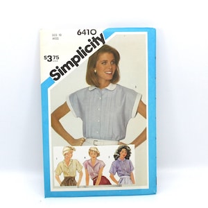 May include: Simplicity sewing pattern number 6410 for a women's blouse. The pattern is for sizes 10 and up. The pattern shows a woman wearing a light blue blouse with a white collar and short sleeves. The pattern also shows three other women wearing different versions of the blouse.