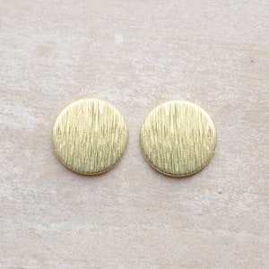 May include: A pair of gold-toned round earrings with a textured surface.