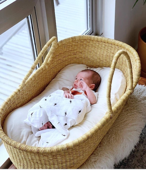 baby sleeps with face against side of moses basket