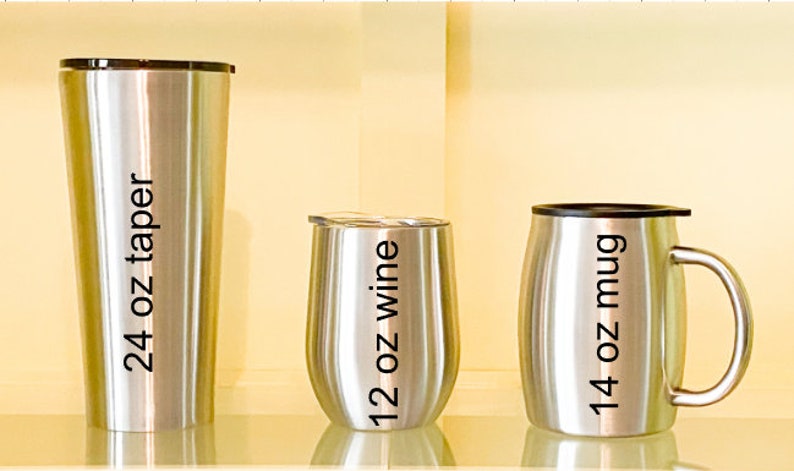 May include: Three stainless steel tumblers with black lettering. The tumblers are labeled "24 oz taper", "12 oz wine", and "14 oz mug".