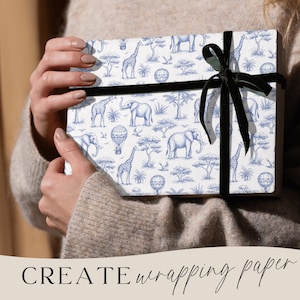 May include: A wrapped gift box featuring a blue and white safari animal pattern, including elephants, giraffes, and hot air balloons. The box is tied with a black ribbon. The words "CREATE wrapping paper" are at the bottom.