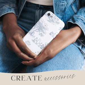 May include: A white phone case with a blue and gray illustration of woodland creatures and trees. The phone case is held in a person's hands, with the text "CREATE accessories" at the bottom.