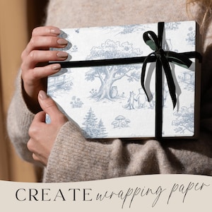 May include: A wrapped gift box featuring a blue and white toile design with forest animals and trees. The box is tied with a black velvet ribbon. The words "CREATE wrapping paper" are at the bottom of the image.