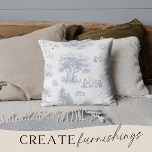 May include: A square throw pillow with a blue and white toile pattern featuring a tree, characters, and other elements. The pillow is surrounded by other pillows in neutral colors. The words "CREATE furnishings" are at the bottom.