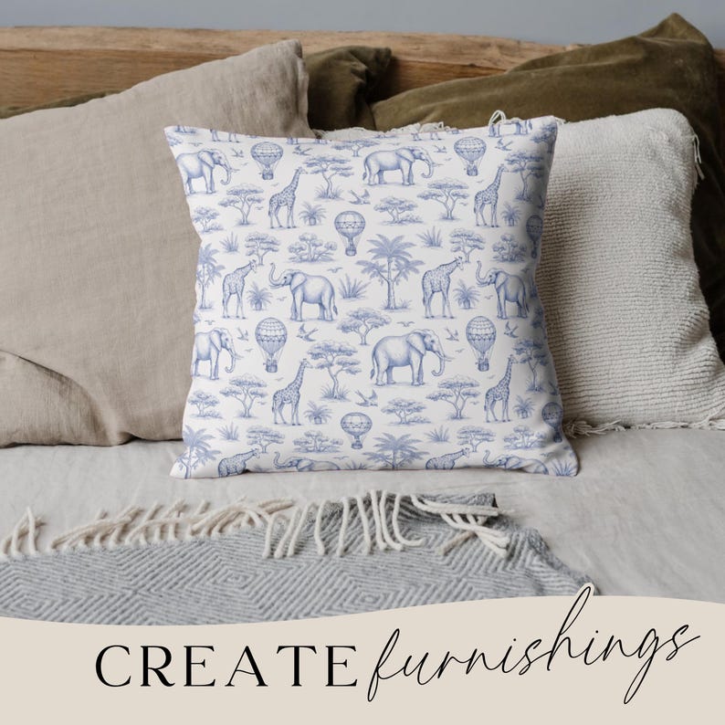 May include: A square throw pillow with a blue and white safari pattern featuring elephants, giraffes, hot air balloons, and trees. The pillow is placed on a bed with other pillows and a blanket. The words "CREATE furnishings" are at the bottom.