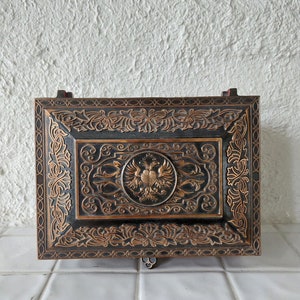 May include: A black wooden box with intricate gold-colored carvings. The box features a central design of a double-headed eagle with a crown.