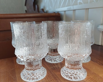 May include: Set of six clear glass drinking glasses with a textured surface. The glasses have a wide base and a rounded bowl.