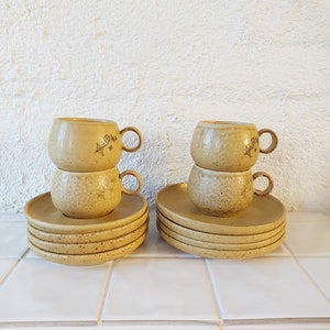 May include: Set of six yellow ceramic teacups and saucers with a textured surface and floral design. The cups and saucers are stacked on top of each other.