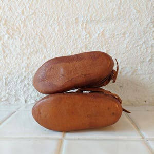 May include: A pair of brown leather baby shoes with laces. The shoes are stacked on top of each other.