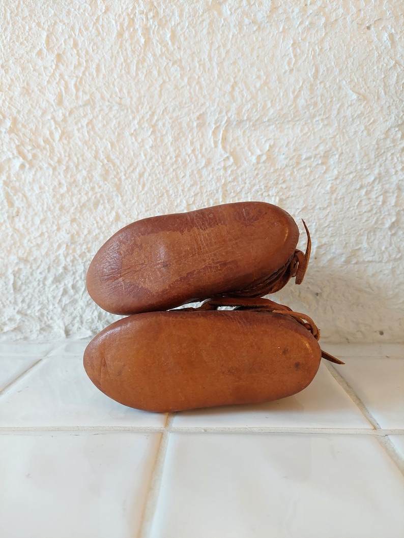 May include: A pair of brown leather baby shoes with laces. The shoes are stacked on top of each other.