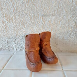 May include: A pair of brown leather ankle boots with laces. The boots are worn and have a distressed look.