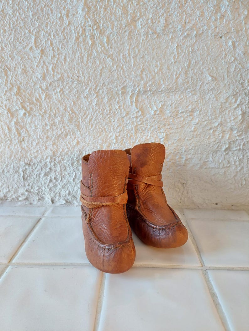 May include: A pair of brown leather ankle boots with laces. The boots are worn and have a distressed look.