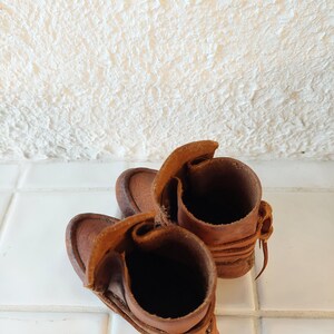 May include: A pair of brown leather boots with laces. The boots are turned inside out, showing the lining.