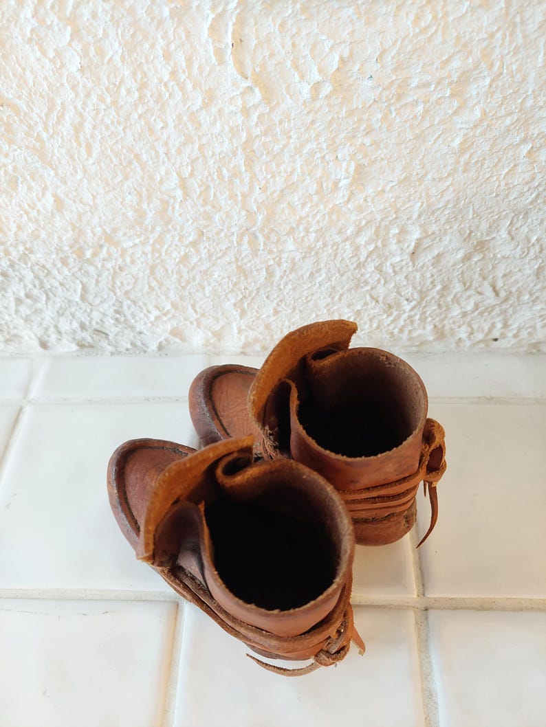 May include: A pair of brown leather boots with laces. The boots are turned inside out, showing the lining.