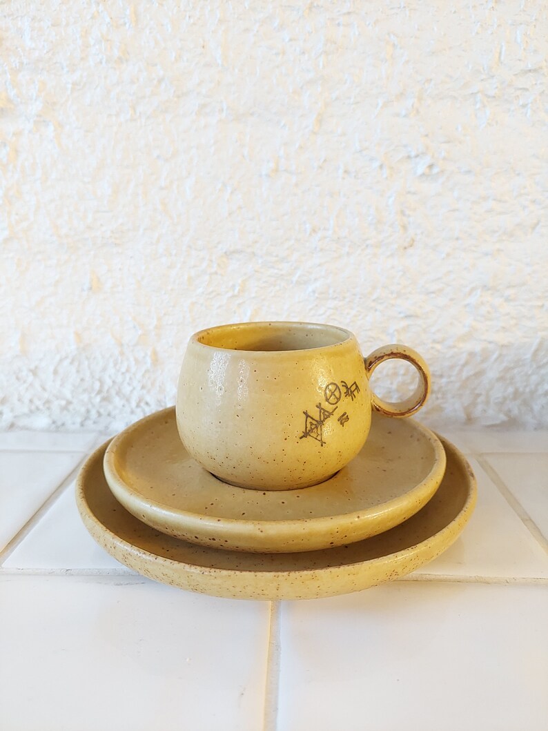 May include: A set of two yellow ceramic saucers and a matching cup with a brown geometric design.