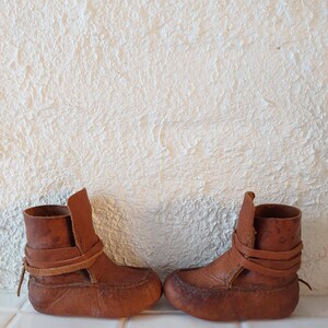 May include: A pair of brown leather ankle boots with laces. The boots are made of a soft, supple leather and have a simple, classic design.