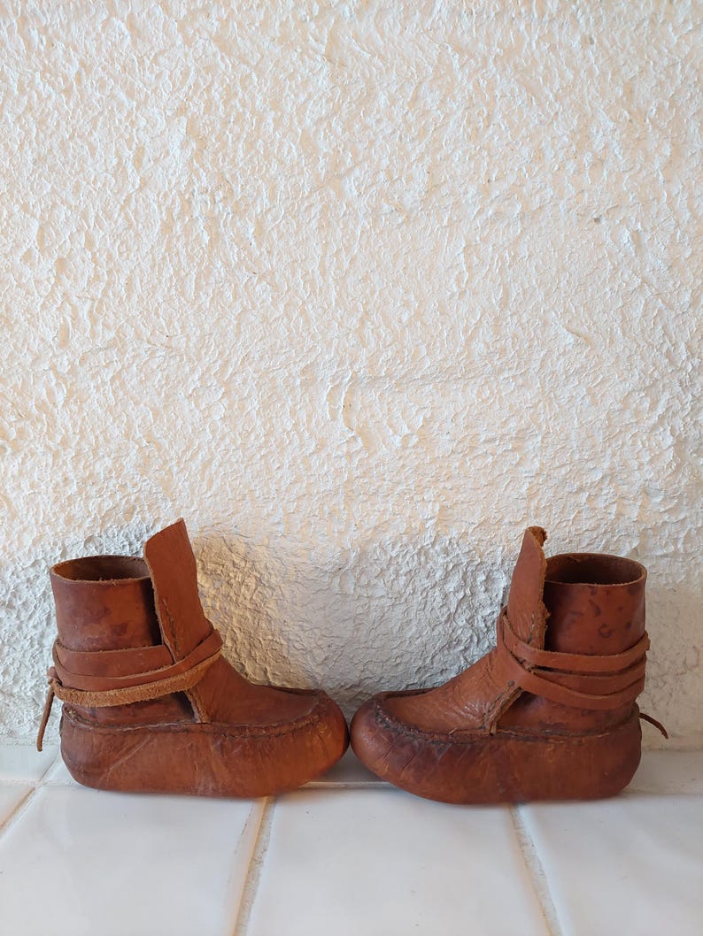 May include: A pair of brown leather ankle boots with laces. The boots are made of a soft, supple leather and have a simple, classic design.