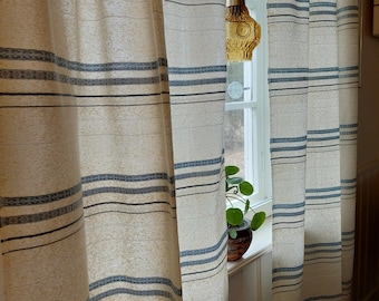 May include: White curtains with blue stripes hang in a window. A small plant sits on the windowsill. A light fixture with a clear glass shade hangs from the ceiling.