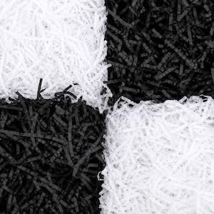 May include: A collection of shredded paper filler arranged in a checkerboard pattern. The material consists of thin, crinkled strips of paper in alternating solid white and solid black colours, creating a high-contrast grid of four distinct sections.